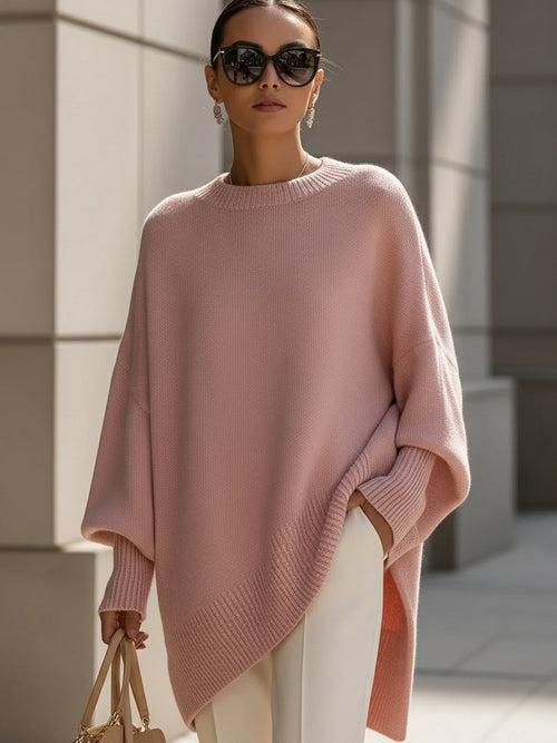 Relaxed poncho-style knit sweater with a round neckline, flowing oversized fit, long draped sides, and ribbed cuffs