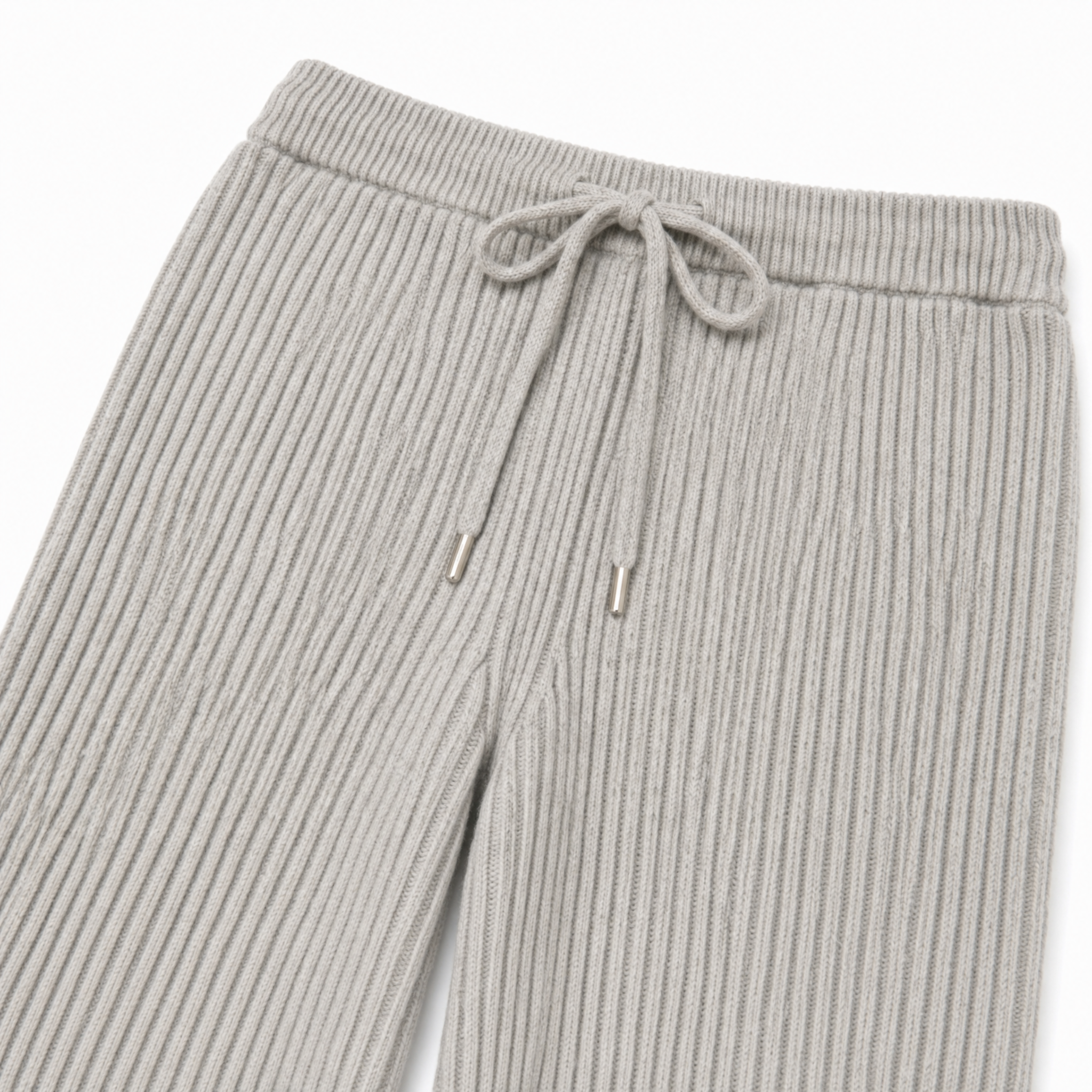Close-up of ribbed knit pants in a light gray color, showing the waistband, drawstring, and ribbed texture against a white background.