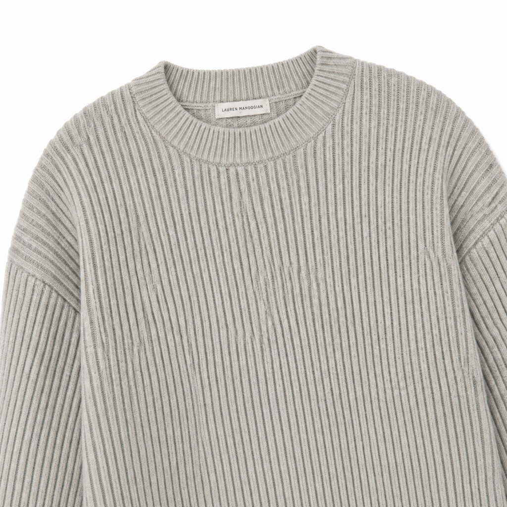 A close-up of a light gray ribbed knit crewneck sweater, showing the vertical texture and a small interior neck label.
